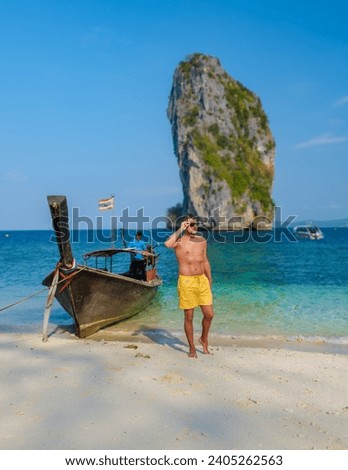 young men at Koh Poda Beach Krabi Thailand, the tropical beach of Koh Poda Island Krabi, a man in swim short walking on the beach, 