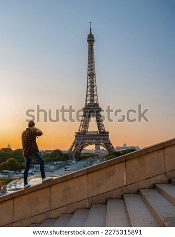Young men photographing the Eiffel tower at Sunrise, a man took a photo of the Eiffel tower Paris. 