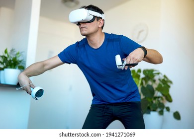 Young Men Playing A Virtual Reality Game At Home Using A VR Headset