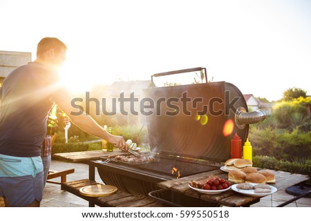 Young men roasting barbecue on grill in cottage countryside.