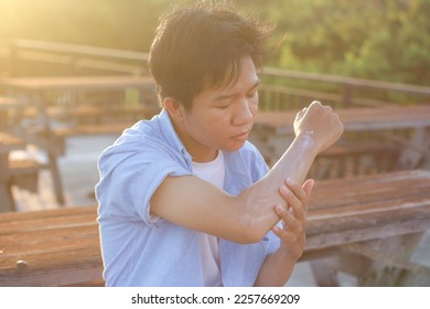 Young men sitting using sunscreen care outdoor - Shutterstock ID 2257669209
