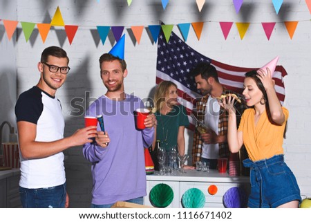 young men smiling at camera while drinking beer and partying with friends