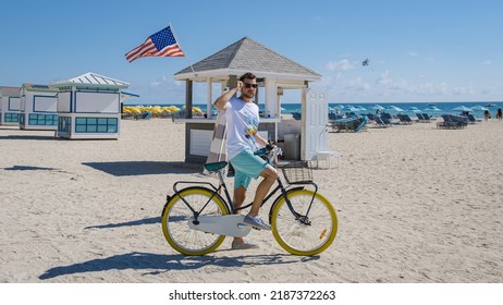 Young men in a swim short on the beach Miami with a bicycle, colorful Miami beach, and a Lifeguard hut in South Beach, Florida.  - Powered by Shutterstock