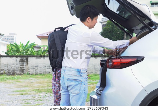 Young men and women carry luggage into\
the trunk of the car preparing to travel by SUV\
car