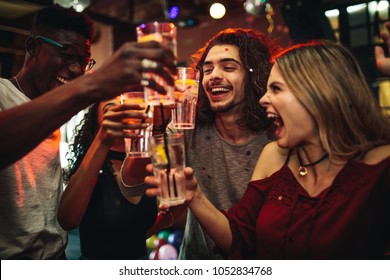 Young men and women celebrating a party, drinking and dancing. Group of friend toasting drinks and having fun at the nightclub. - Powered by Shutterstock
