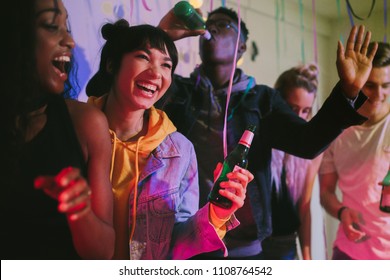 Young Men And Women Enjoying At The House Party. Friends Laughing And Dancing Holding Drinks At House Party.