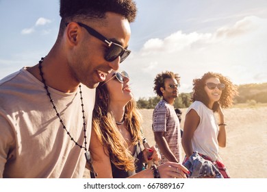 Young men and women friends walking on coast - Shutterstock ID 667889167