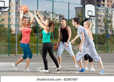 Young Men And Women Playing Basketball In A Park