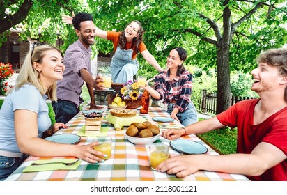 Young men and women toasting healthy orange fruit juice at farm house patio picnic - Life style concept with happy friends having fresh fun together on afternoon relax time - Bright vivid filter - Powered by Shutterstock