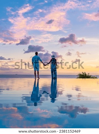 Young men and women watching the sunset with reflection in the infinity swimming pool at Saint Lucia Caribbean, couple at infinity pool during sunset on a luxury vacation at St Lucia