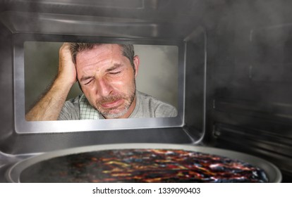 Young Messy And Funny Dummy Man In The Kitchen Looking Through Microwave Or Oven Pizza Burning Overcooked Making A Mess Of Home Cook In Domestic Disaster And Lifestyle Concept