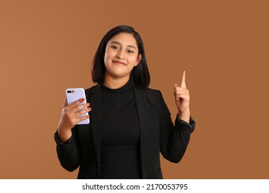 young mexican brunette business woman holding phone, smiling having an idea on plain brown background - Shutterstock ID 2170053795