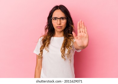 Young mexican woman isolated on pink background standing with outstretched hand showing stop sign, preventing you.