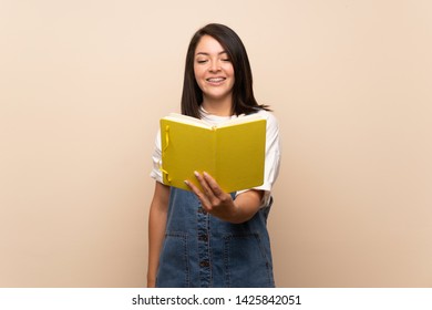 Young Mexican woman over isolated background holding and reading a book - Shutterstock ID 1425842051