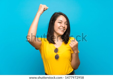 Young Mexican woman over isolated blue background celebrating a victory