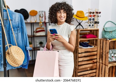 Young Middle East Customer Woman Holding Shopping Bags And Using Smartphone At Clothing Store.