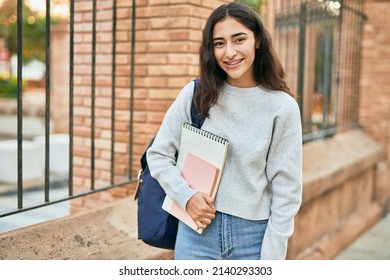 Young middle east student girl smiling happy holding book at the city.