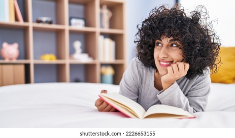 Young middle east woman reading book lying on bed at bedroom - Shutterstock ID 2226653155