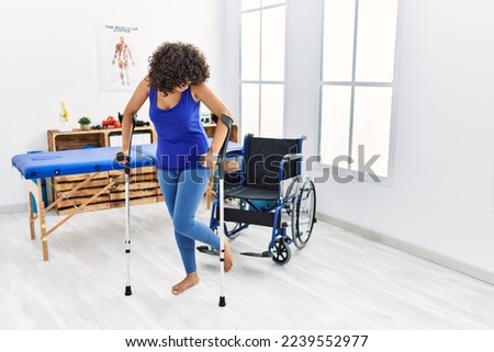Young middle east woman walking using crutches at clinic
