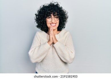 Young Middle East Woman Wearing Casual White Tshirt Praying With Hands Together Asking For Forgiveness Smiling Confident. 