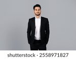 A young Middle Eastern businessman stands confidently in a studio setting. His formal attire and demeanor reflect his entrepreneurial spirit and professionalism in a corporate environment.