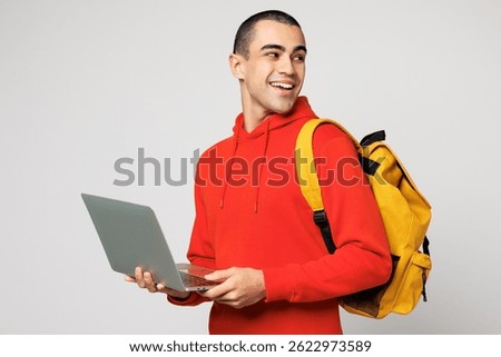 Young IT middle eastern man boy student wears red casual clothes backpack bag hold books work use laptop pc computer isolated on plain solid white background. High school university college concept