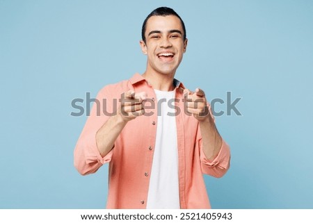 Young middle eastern man he wears pink shirt white t-shirt point index finger camera on you motivate encourage isolated on plain pastel light blue cyan background studio portrait. Lifestyle concept