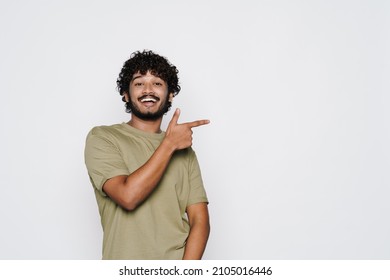 Young middle eastern man smiling and pointing finger aside isolated over white wall