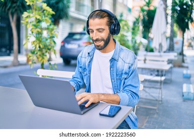 Young Middle Eastern Man Working Using Laptop And Headphones At Coffee Shop Terrace.