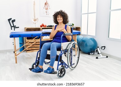 Young Middle Eastern Woman Sitting On Wheelchair At Physiotherapy Clinic Smiling With Hands On Chest With Closed Eyes And Grateful Gesture On Face. Health Concept. 