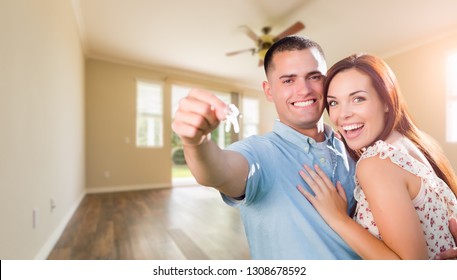 Young Military Couple With House Keys In Empty Room Of New Home.