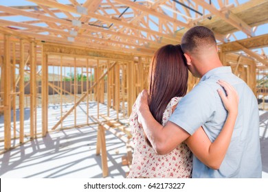 Young Military Couple On Site Inside Their New Home Construction Framing.