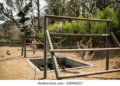 Young military soldiers practicing rope climbing during obstacle course at boot camp - Powered by Shutterstock