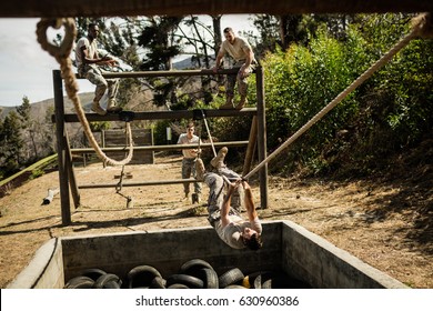 Young military soldiers practicing rope climbing during obstacle course at boot camp - Powered by Shutterstock