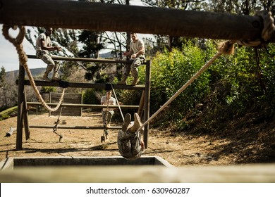 Young military soldiers practising rope climbing during obstacle course at bootcamp - Powered by Shutterstock