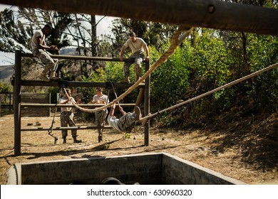 Young military soldiers practising rope climbing during obstacle course at bootcamp - Powered by Shutterstock