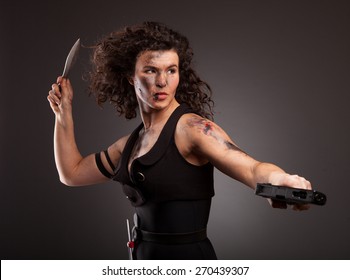 Young military woman posing with knife. Ready to fight. With dirty face, wound and blood.