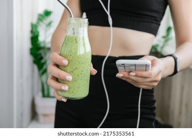 Young millenial woman checking smartphone drinking vegan smoothie drink detox. Woman doing yoga exercises at home. Online tuition Clean eating, weight loss, healthy dieting food concept. Stay healthy - Powered by Shutterstock