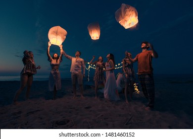 Young millenials holding and igniting sky lantern - Lantern festival on the beach - Powered by Shutterstock