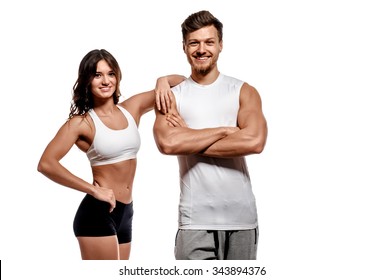Young millennial beautiful athletic brunette woman and handsome man posing on white background studio shot. Wearing sport wear standing looking at camera smiling. Healthy positive cheerful people.