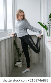 Young Millennial Blonde Woman Doing Yoga Exercise Stretching Fitness At Balcony Home. Mindfulness Meditation. Relax Breathe Easy Pose Gym Healthy Lifestyle Concept.