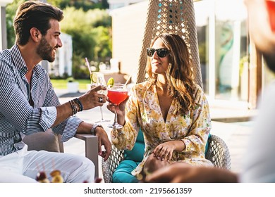 A Young Millennial Generation Couple Celebrates A Toast Sitting In The Resort Garden Clinking Glasses With Imaginative Cocktails - Backyard Recreation - People And Lifestyle Concept