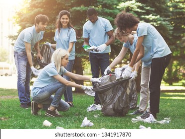 Young millennial volunteers picking garbage in park, ecology protection concept, free space - Powered by Shutterstock