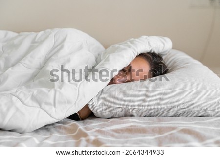 Young millennial woman sleeping covered with blanket. Cold winter. No heating at home. Loud snoring. Sweet dreams. Circadian cycles.