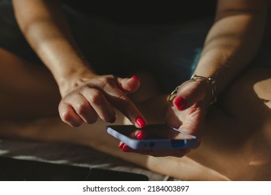 Young Millennial Woman Texting On Mobile Device. Hands Of A Woman Wearing Bright Red Nail Polish In Frame, Closeup.