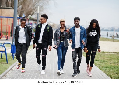 Young millennials african friends walking in city. Happy black people having fun together. Generation Z friendship concept.