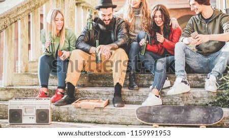 Young millennials friends drinking beer and eating pizza outdoor in city center - Happy people having fun listening music and doing party outside - Generation z, youth lifestyle and fashion concept 