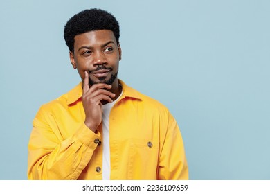 Young minded pensive thoughtful man of African American ethnicity 20s he wear yellow shirt look aside prop up chin think isolated on plain pastel light blue background studio. People lifestyle concept - Powered by Shutterstock