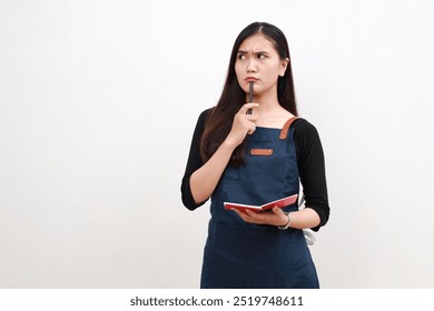 Young minded thoughtful asian woman barista employee wear blue apron work in coffee shop write down order in notebook isolated on white background. Small business startup concept - Powered by Shutterstock