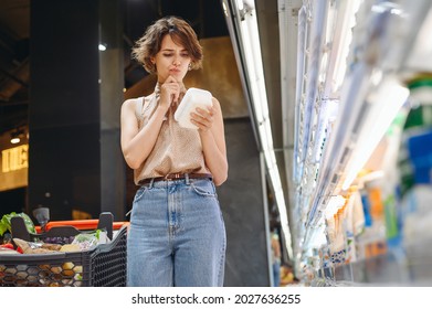 Young Minded Woman 20s In Casual Clothes Backpack Shopping At Supermaket Store Buy Dairy Produce Take Hold Container Read Shelf Life Prop Up Chin Inside Hypermarket Purchase Gastronomy Food Concept